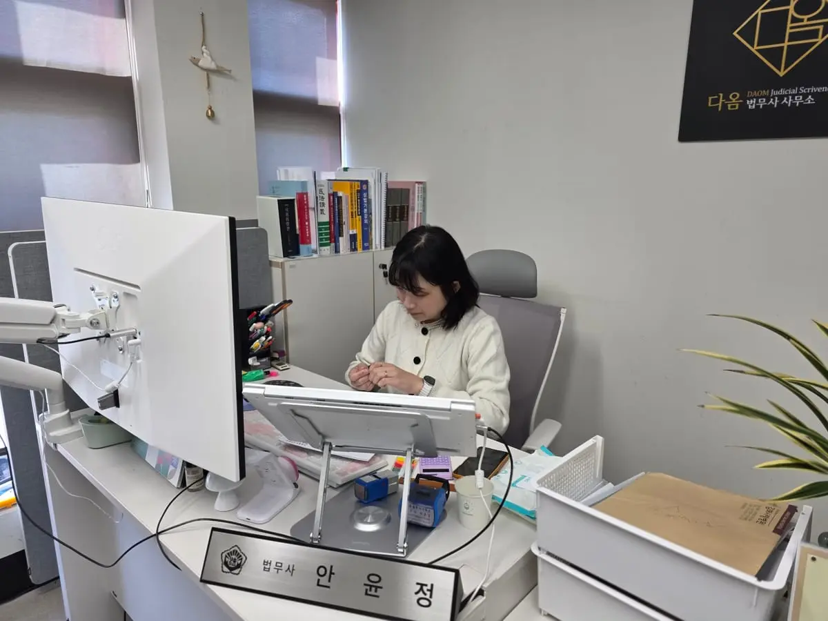 명패가 놓인 책상에서 서류를 살펴보는 법무사
