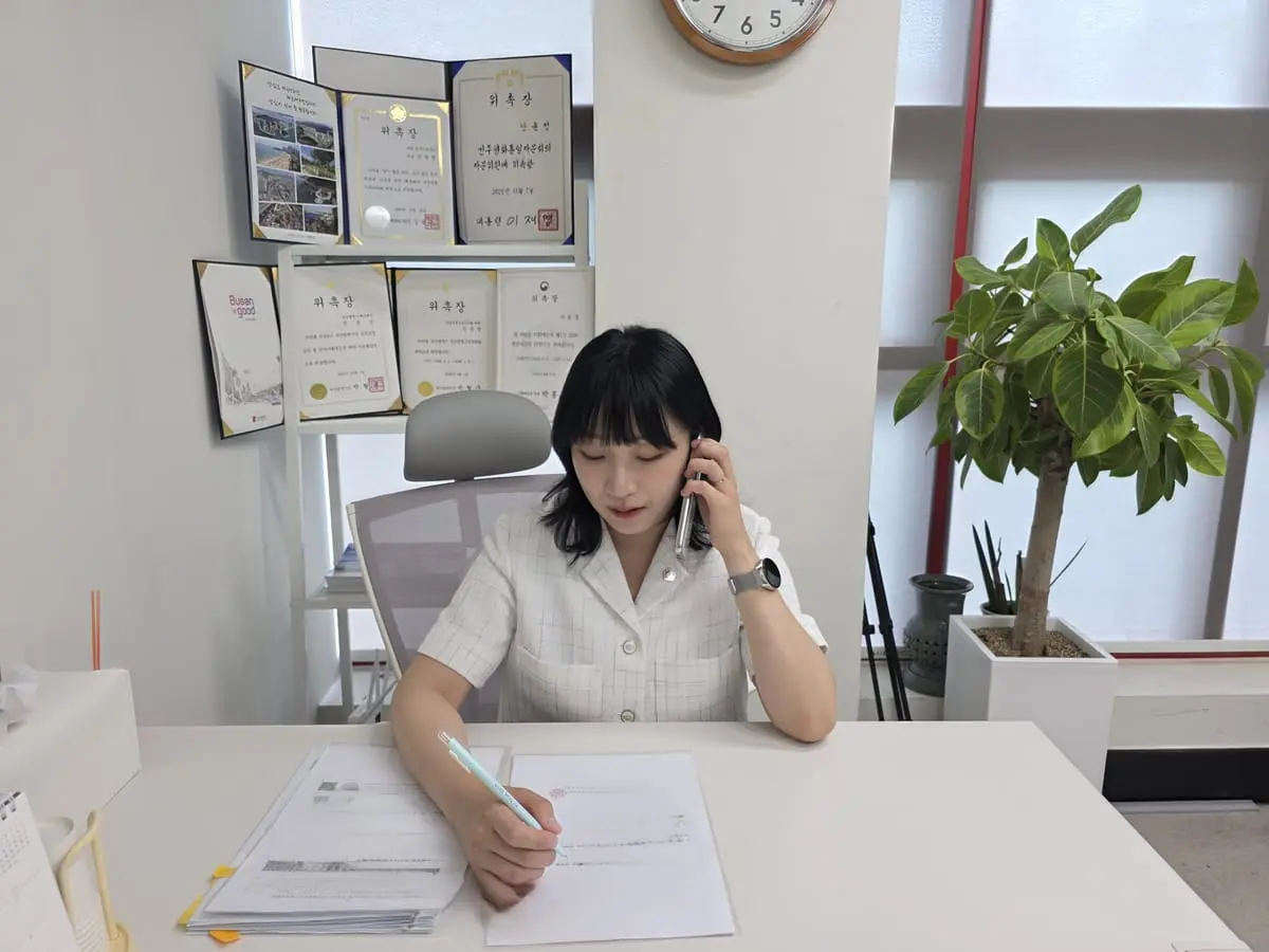 사무실 책상에서 전화로 상담하며 메모하는 모습