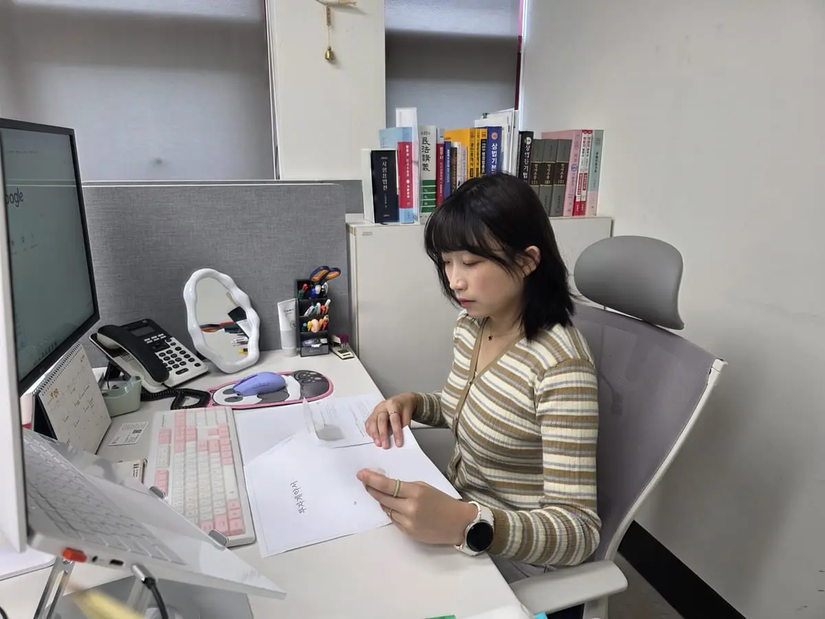 다옴법무사사무소 책상에서 서류를 펼쳐 놓고 검토하는 모습