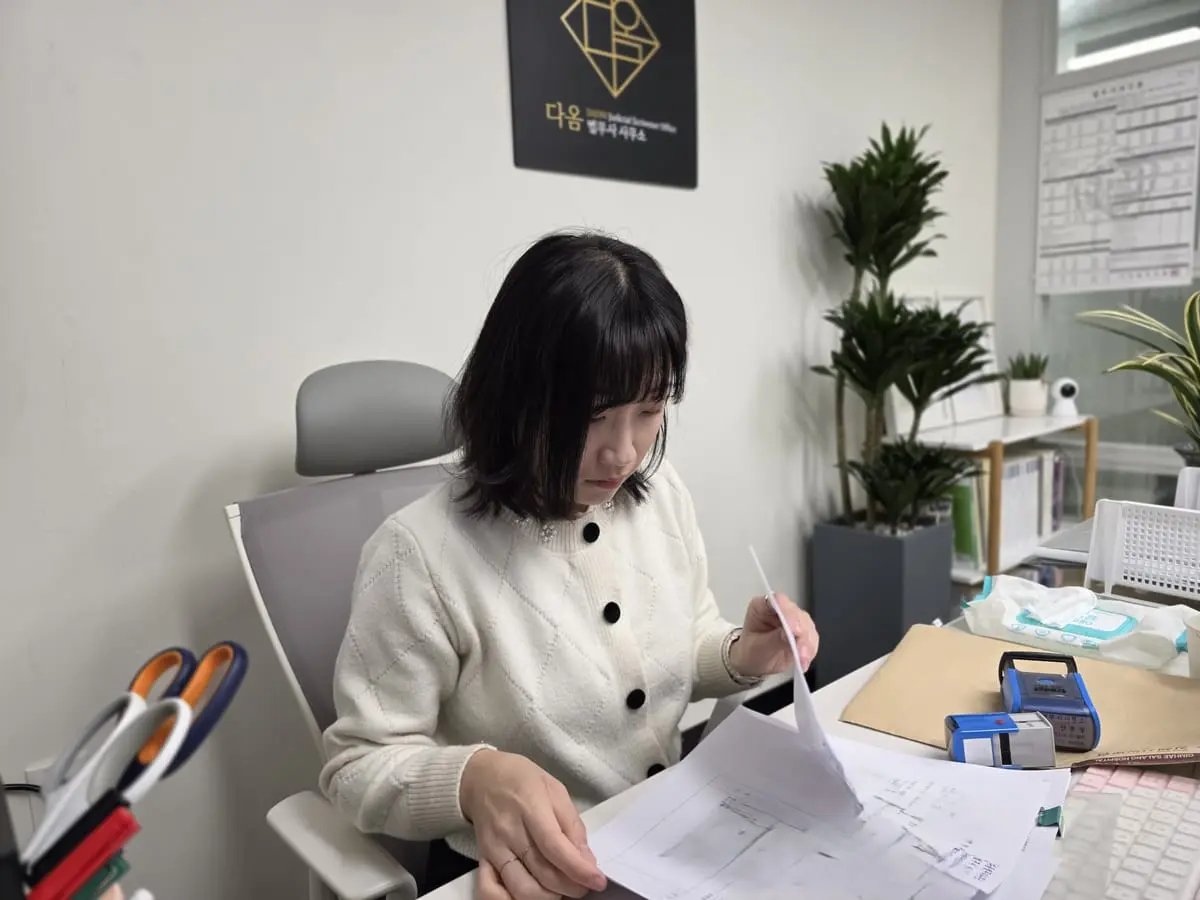 다옴법무사사무소에서 서류를 넘기며 확인하는 모습, 뒤편에 사무소 간판