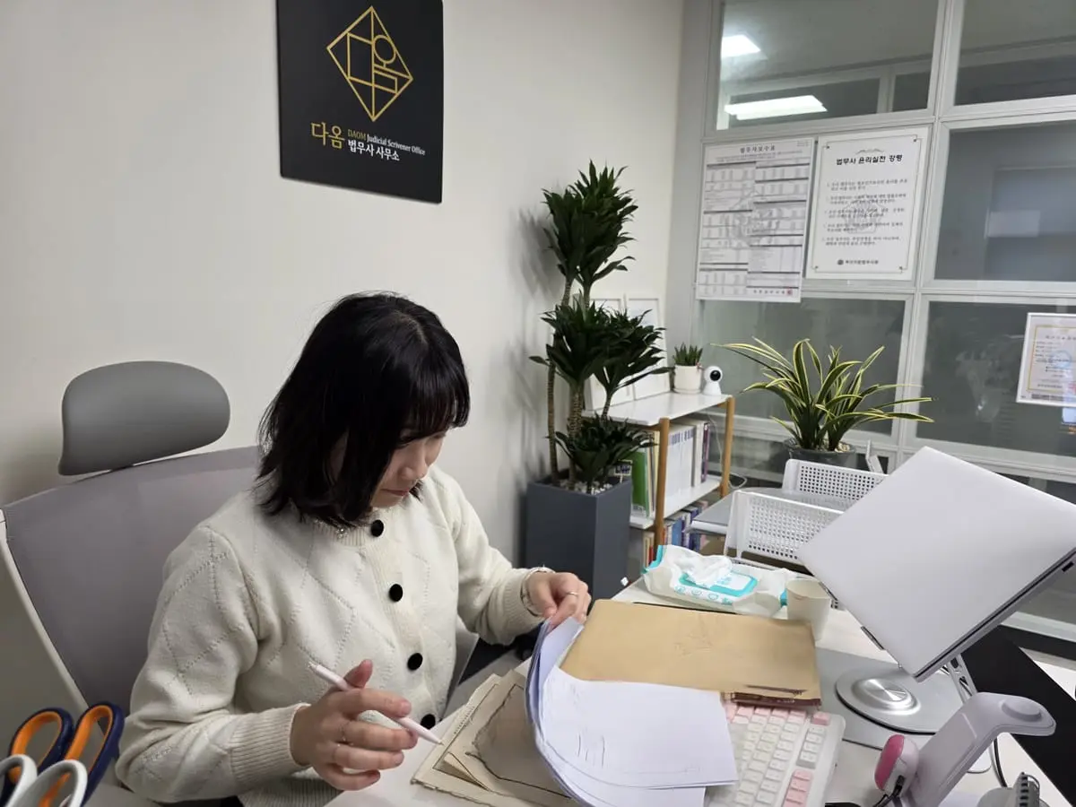 다옴법무사사무소에서 오래된 서류 묶음을 넘기며 확인하는 모습