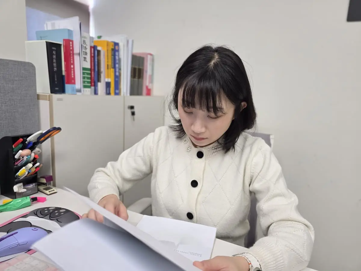책상에서 서류를 한 장씩 넘겨 확인하는 모습