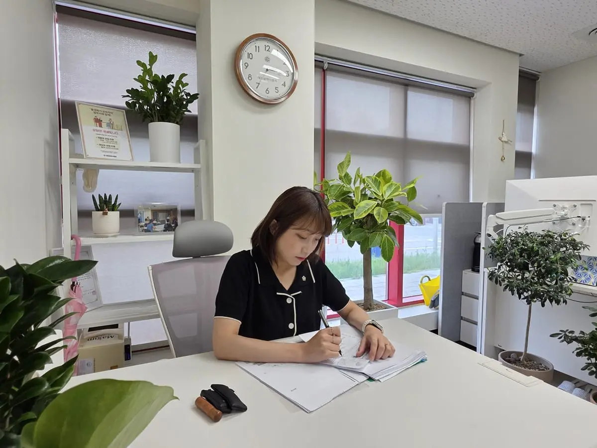 창가 책상에서 서류에 메모하며 검토하는 모습